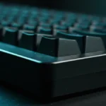 Close lateral da borda de um teclado mecânico escuro sob luz fria